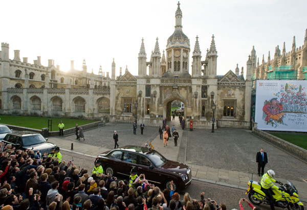 A different, wide perspective shows the Queen leaving Cambridge University to crowds of people.